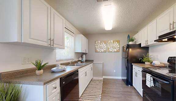 A kitchen with black appliances and white cabinets at Fountains of Largo in Largo, FL