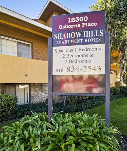 A sign for Shadow Hills Apartment Homes is in front of a building.