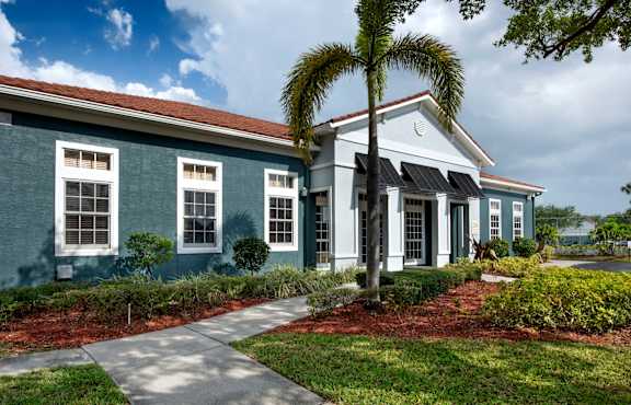 A blue house with a white trim and a palm tree in front.