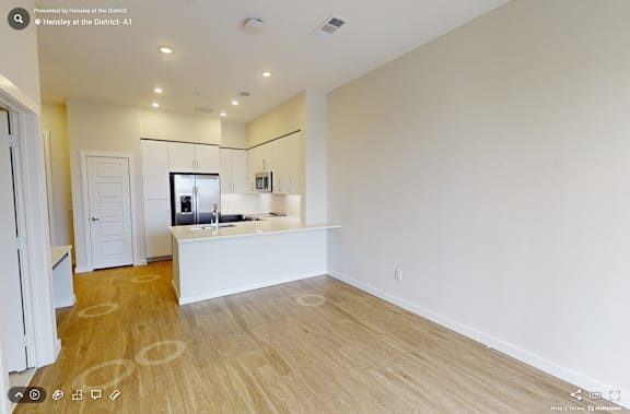 A spacious, empty room with wooden flooring and white walls.