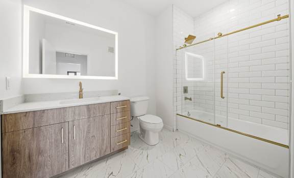 A white bathroom with a wooden vanity and a white toilet.