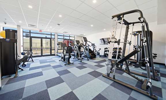 A gym with a variety of equipment including a treadmill, weights, and a bench press.