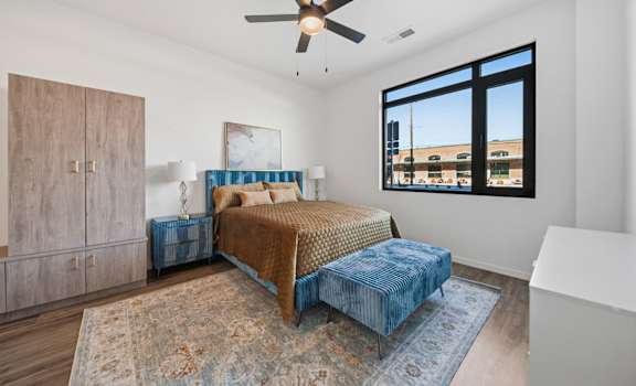 A bedroom with a bed, dresser, and a ceiling fan.