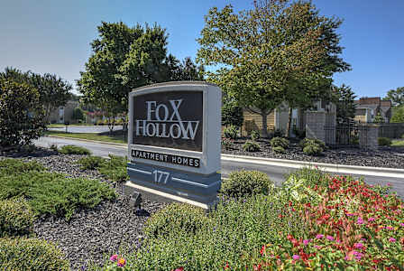 A sign for Fox Hollow Apartment Homes stands in front of a well-manicured garden. at Fox Hollow Apartment Homes, High Point, NC, 27265