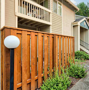 A wooden fence with a white lamp post in front of a house.