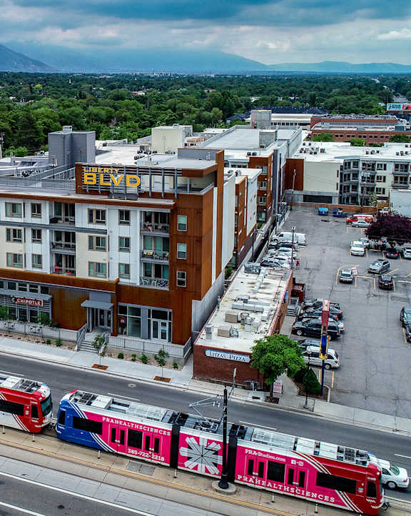 A train is on the tracks in front of a building with the word "Bed" on it. at Liberty Blvd Apartments - Saltlake City, UT Apartments, Apartments, Saltlake City, UT