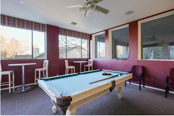 A pool table in a room with a ceiling fan.