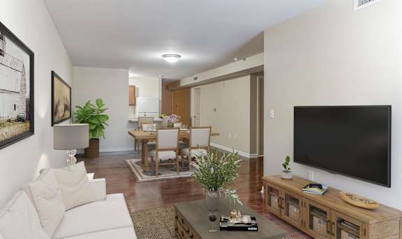 A living room with a white couch, a wooden coffee table, and a large flat screen TV mounted on the wall at 13 State Street Apartments in Schenectady, NY