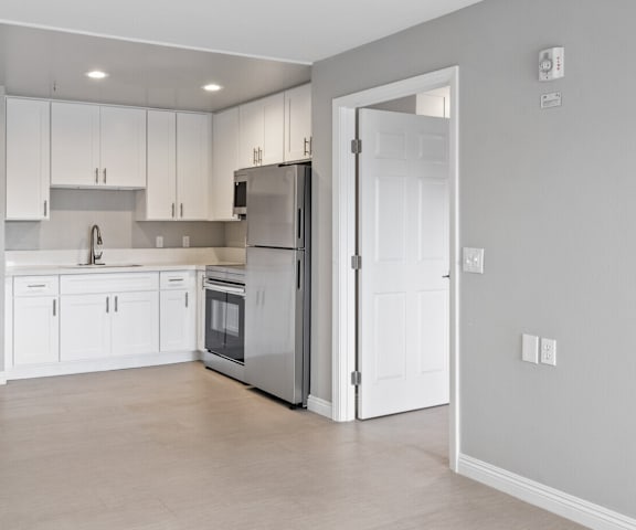a kitchen with white cabinets and a stainless steel refrigerator