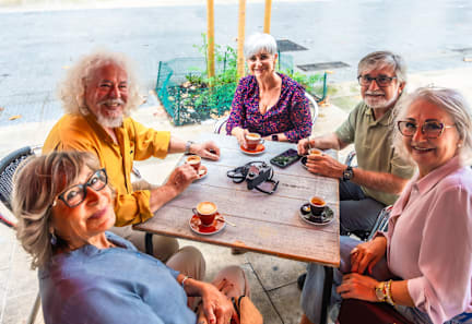 Four older people sitting at a table outside.