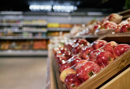 A row of red apples are on display in a store.