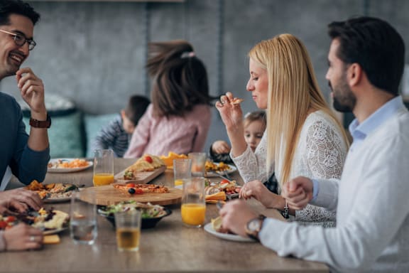 A group of people are sitting around a table eating food.
