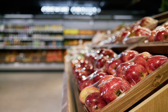 A row of red apples are on display in a store.