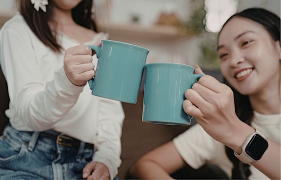 Two people holding blue mugs and smiling.