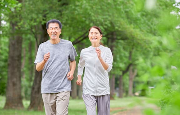 An older couple jogging in a park.