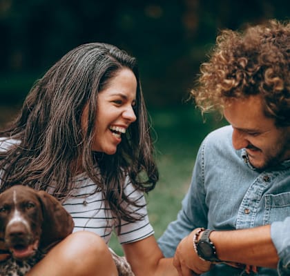 A man and woman sitting on the ground with a dog between them.