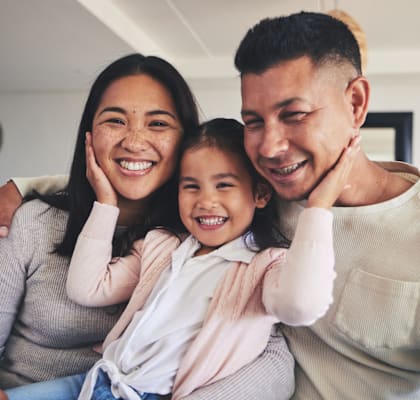 A family of three is sitting closely together, sharing a joyful moment.