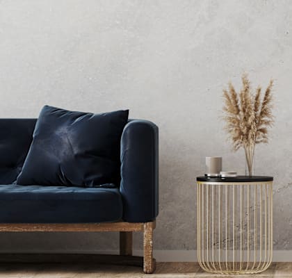 A dark blue couch with a black side table and a plant on it.