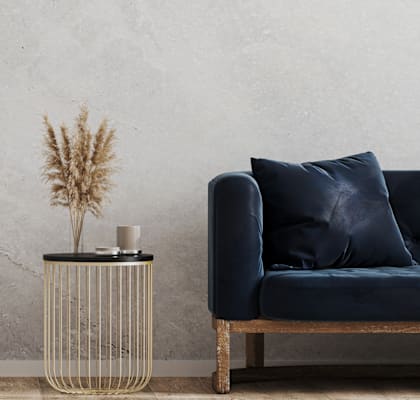 A black couch with a gold side table and a plant on it.
