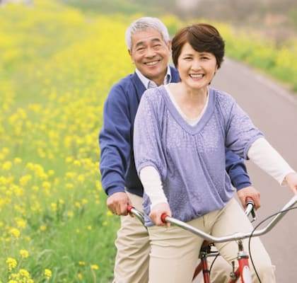 An older couple riding a bicycle together.