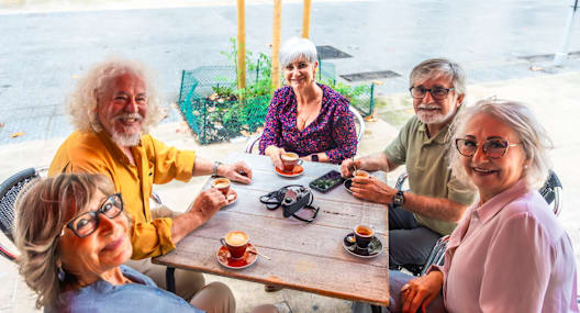 Four older people sitting at a table outside.