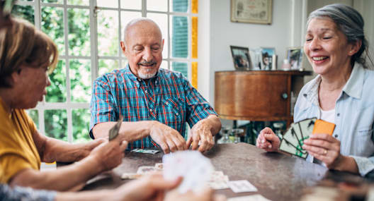 A group of people playing a card game at a table.