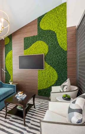 A sitting room featuring a blue sofa, two white chairs, a coffee table, and a wall-mounted TV