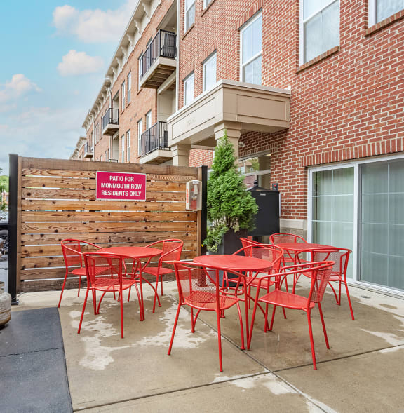 a kitchen with white cabinets and a white island with chairs at Monmouth Row Apartments, Newport, KY, 41071