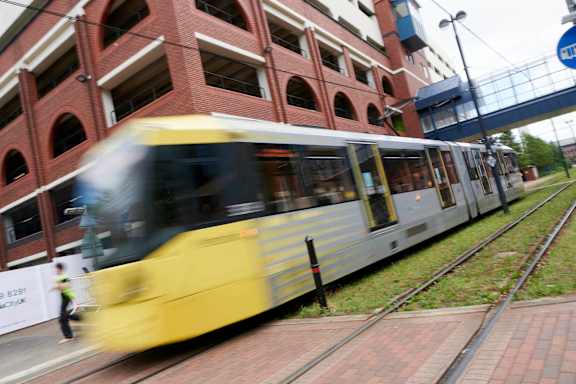 A yellow and white train is moving along the tracks.