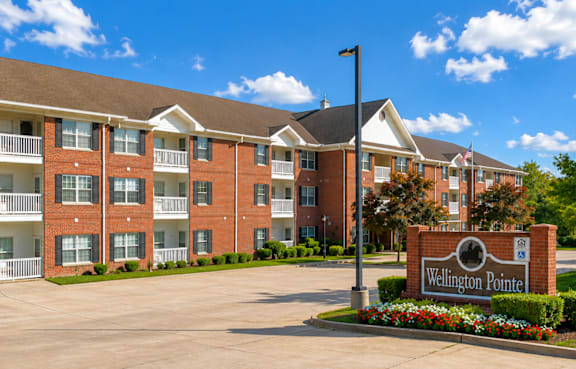 A large brick building with a sign that says Wellington Point in front of it.