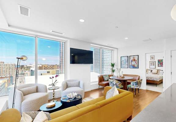 A living room with a yellow couch and a flat screen TV.