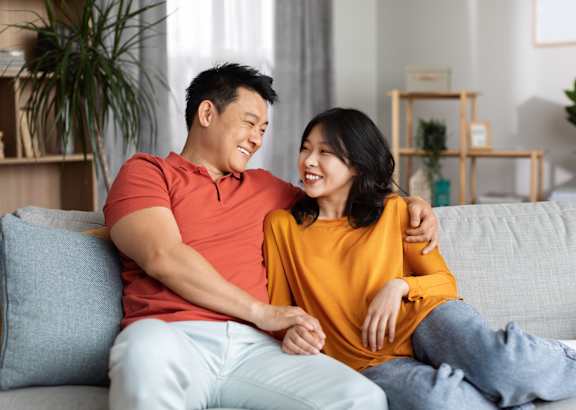A man and woman are standing in a kitchen, sharing a moment together.