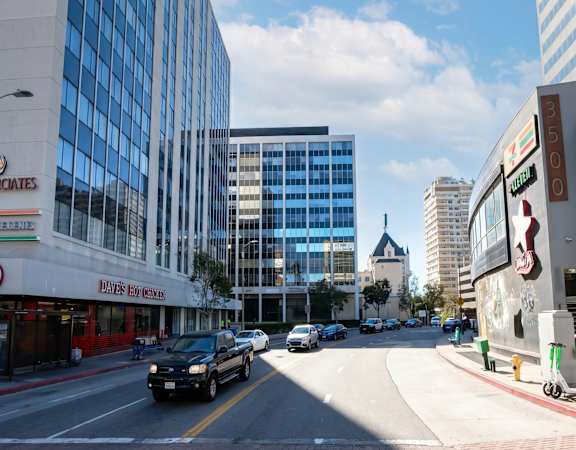 A city street with cars and buildings on either side.