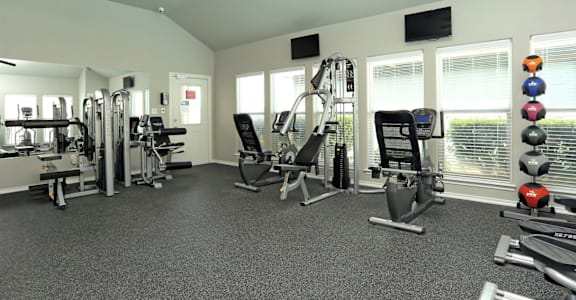 A spacious gym with a variety of equipment including a treadmill, a stationary bike, a rowing machine, a bench press, a squat rack, a leg press machine, a cable machine, a d