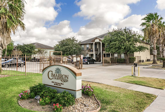 A sign for Cimarron Country Club in front of a building and trees.