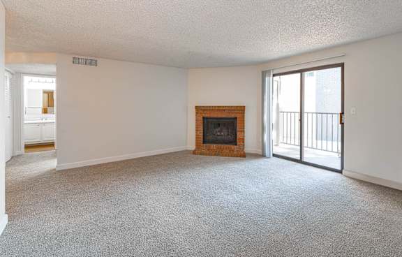 an empty living room with a fireplace and a sliding glass door