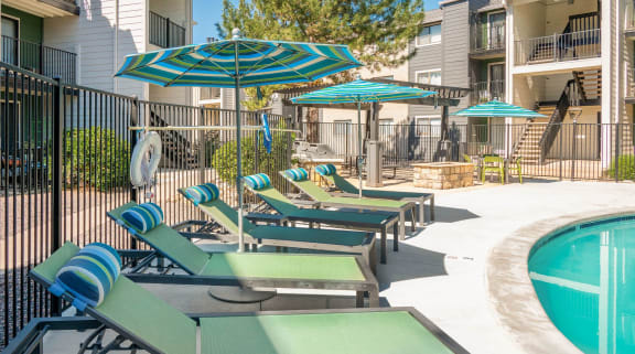 a row of lounge chairs with umbrellas next to a pool