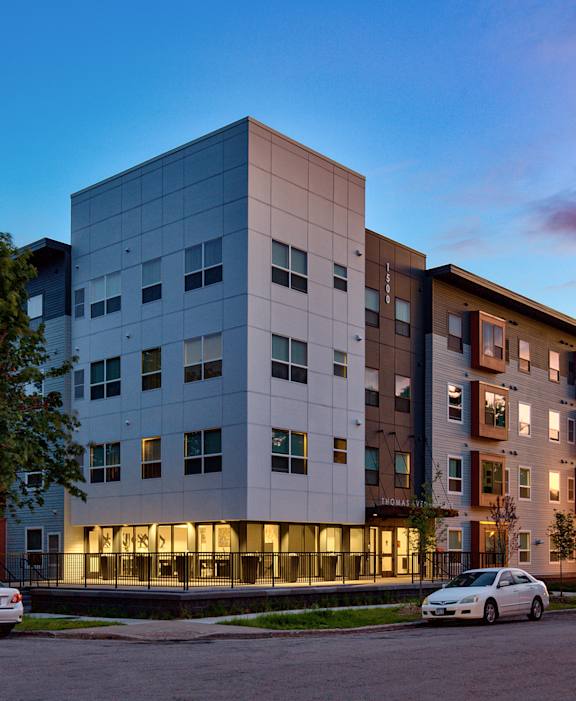 A modern apartment building with cars parked in front.