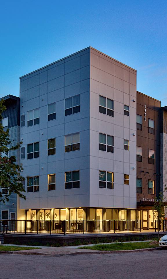 A modern apartment building with cars parked in front.