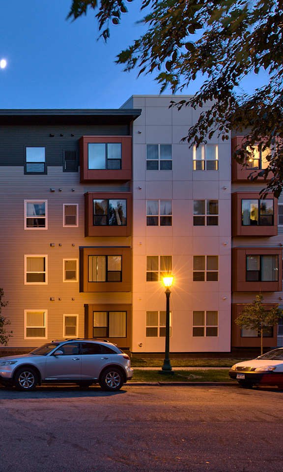 A modern apartment building with cars parked in front.