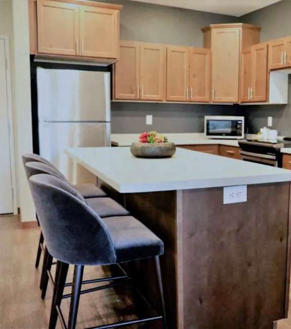 A kitchen with a white island and wooden cabinets.