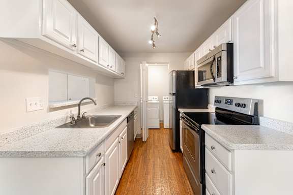 a kitchen with white cabinets and black appliances and a sink
