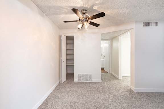 a living room with a ceiling fan and a closet