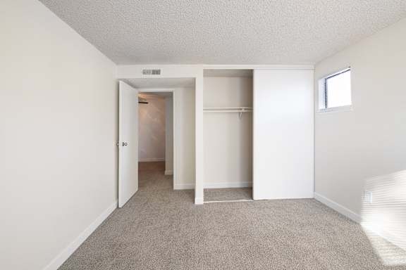 an empty bedroom with white walls and a closet