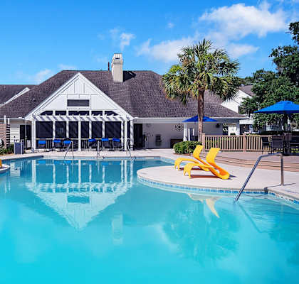 A swimming pool with yellow chairs and a building in the background.