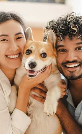 Man and Woman Smiling while Sitting on Couch with Dog