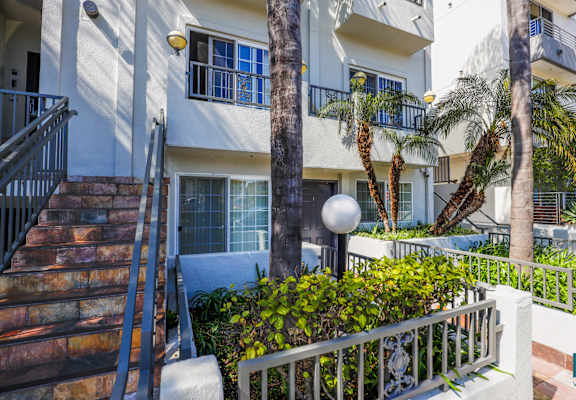 a white apartment building with stairs and palm trees