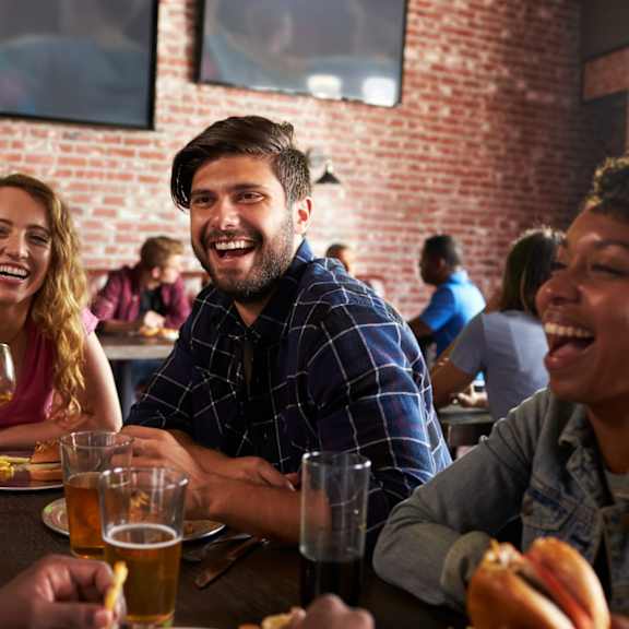 Friends Smiling while Having Dinner and Drinks Together