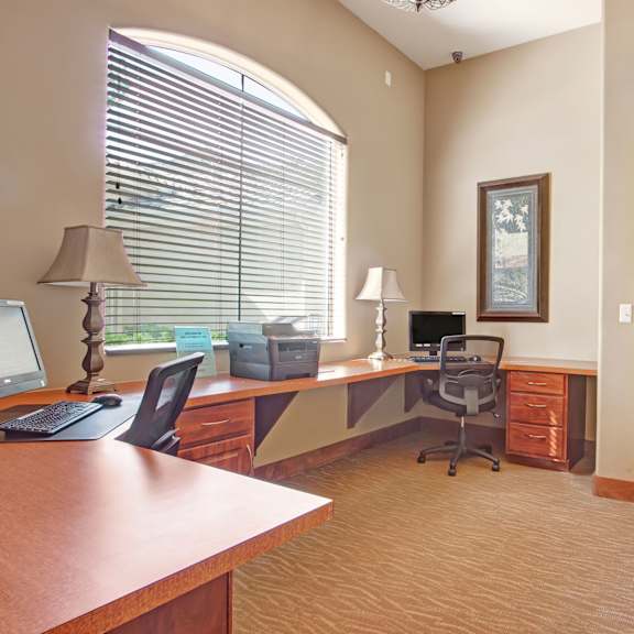 The business center at Rancho Belago with a desk, chairs, and two desktop computers. 