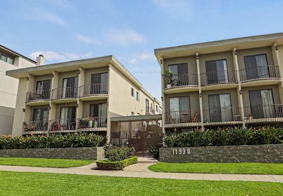 Two apartment buildings with balconies and a fire hydrant in the foreground.